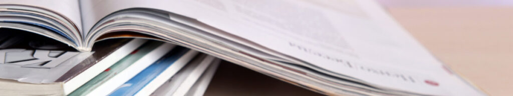 A close-up low-angle view of a stack of journals on a desk. One issue is open on top.